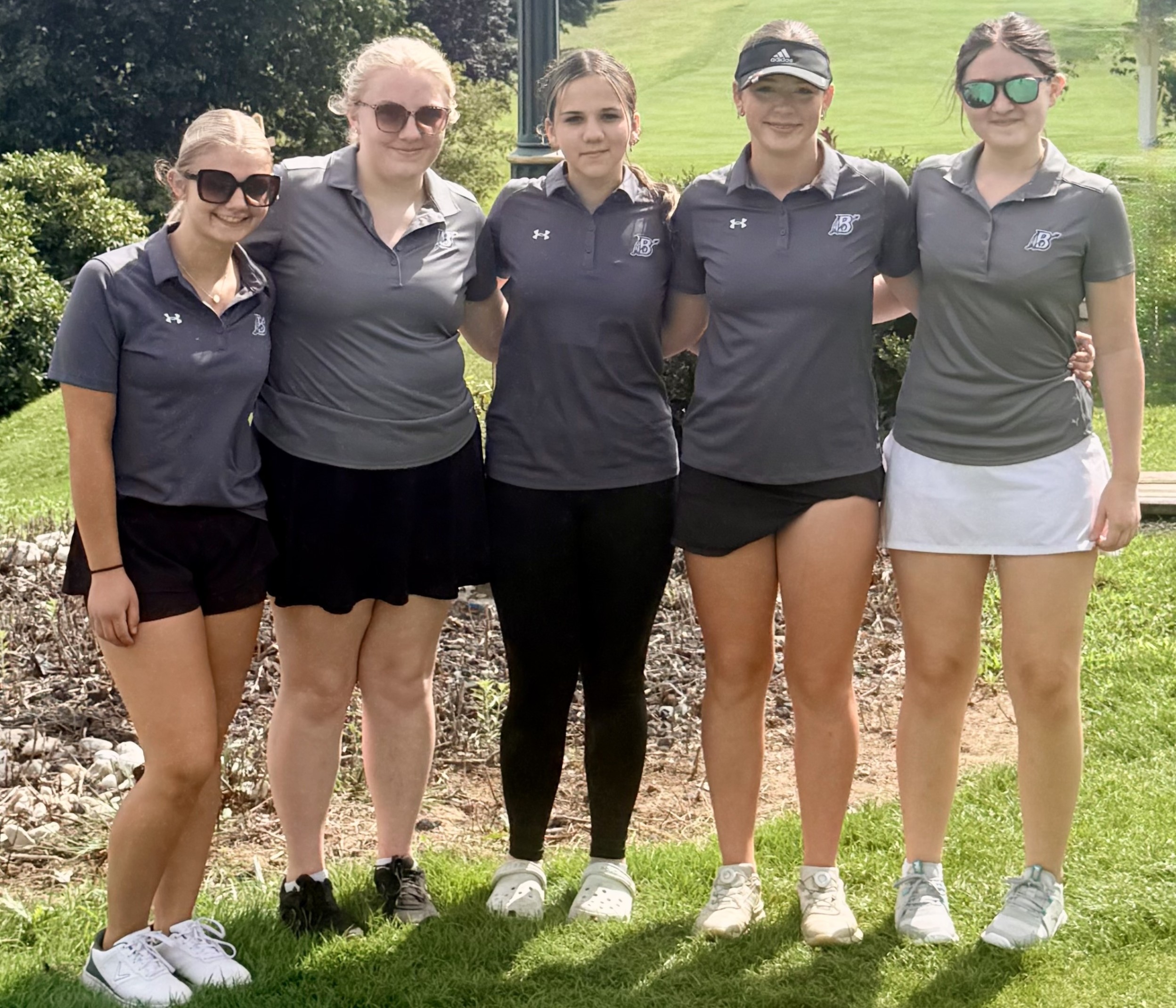 Five members of the girls golf team pose for a photo recently on a golf course.